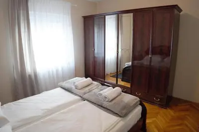 a bedroom with a large wooden cabinet with towels on a bed at Apartmani Kula - Lux Apartman in Novi Banovci
