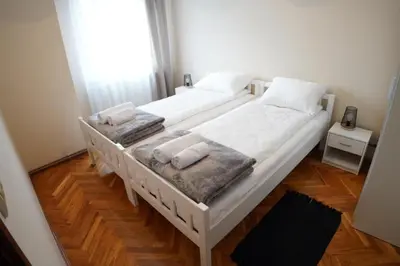 two beds in a bedroom with white sheets and towels at Apartmani Kula - Lux Apartman in Novi Banovci