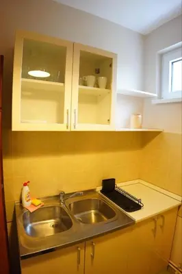 a kitchen with a stainless steel sink and white cabinets at Apartmani Kula - Apartman 2 in Novi Banovci