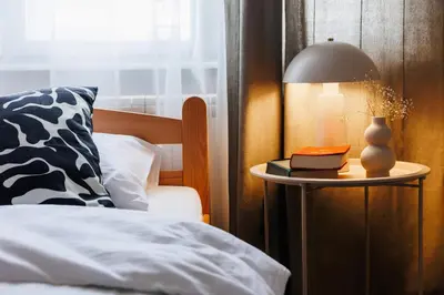 a bed with a lamp and a book on a side table at Harmonic Nest 3min to Republic Square Renovated in Belgrade