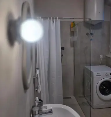 a bathroom with a shower and a washing machine at Boneca apartment in Belgrade
