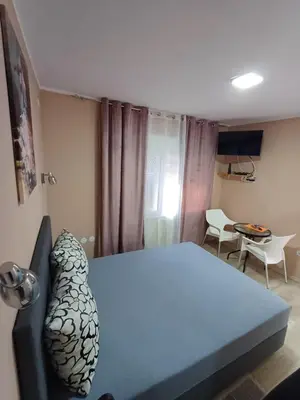 a bedroom with a blue bed and a table and chairs at Apartments DAJER in Arandjelovac