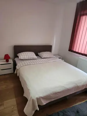 a bedroom with a large white bed and a window at EM Apart in Beograd