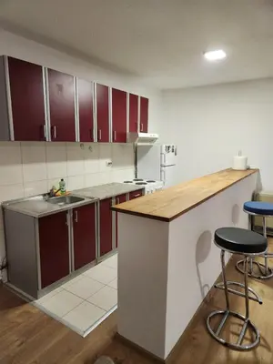 a kitchen with red cabinets and a counter with stools at EM Apart in Beograd