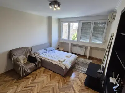 a bedroom with a bed and a couch and a window at Sunny Lux Apartment Terazije in Belgrade
