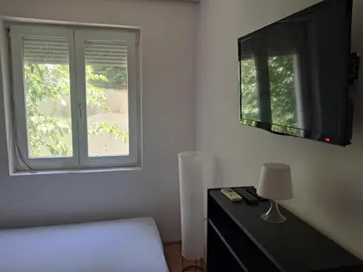 a bedroom with a bed and a window and a lamp at Quiet garden in Belgrade