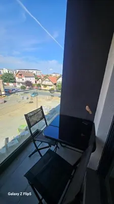 a bird sitting on a table and a chair on a balcony at Apartman Mima in Inđija