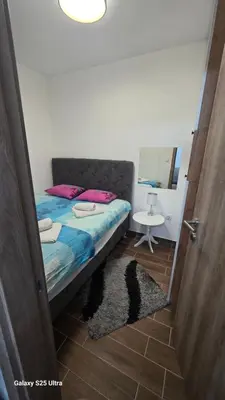 a bedroom with a bed and a table and a mirror at Apartman Mima in Inđija