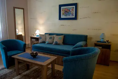 a living room with a blue couch and two chairs at Guest House A'storia in Ruma