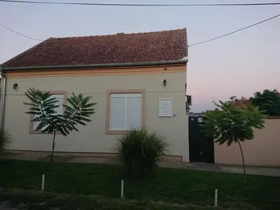 a white house with a black door and two trees at Guest House A'storia in Ruma