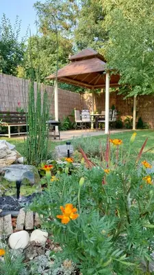 a garden with flowers and a gazebo in a yard at Guest House A'storia in Ruma