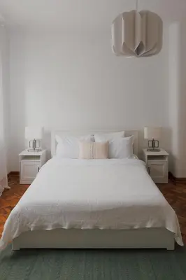 a white bedroom with a white bed with two tables at Radio Belgrade Apartment in Belgrade