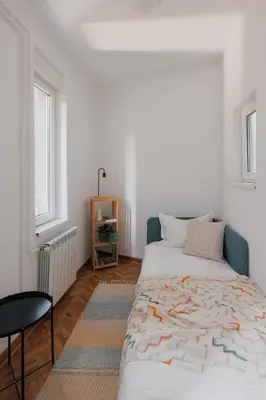 a bedroom with a bed and a chair and a window at Radio Belgrade Apartment in Belgrade