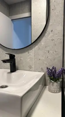 a bathroom sink with a mirror and a vase of purple flowers at District 21 in Belgrade