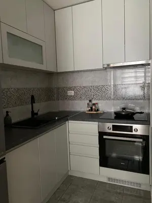 a kitchen with white cabinets and a sink and a stove at Apartman Oaza in Smederevo