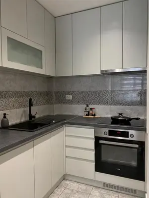 a kitchen with white cabinets and a stove and a sink at Apartman Oaza in Smederevo