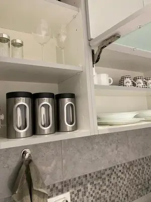 a kitchen cabinet with two silver and black coffee mugs at Apartman Oaza in Smederevo