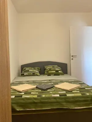 a bedroom with a bed with a green and white bedspread at Zmaj LUX in Mladenovac