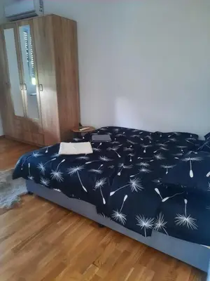 a bed with a blue blanket with dandelions on it at Zmaj LUX in Mladenovac