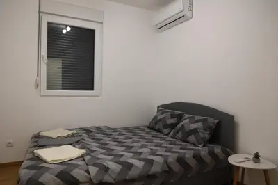 a small bedroom with a bed and a window at Zmaj LUX in Mladenovac
