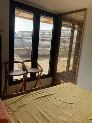 a bedroom with a bed and a chair and windows at Krov in Belgrade