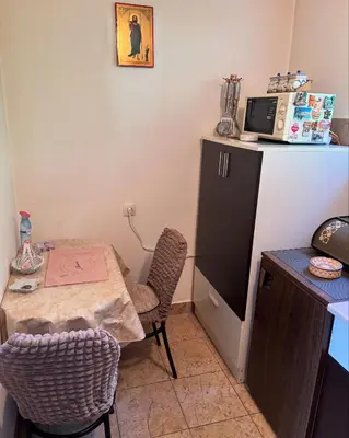 a small kitchen with a table and a refrigerator at Kuća na obali Save in Obrenovac