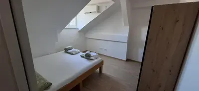 a small white room with a bench and a staircase at Bingo's apartman in Belgrade