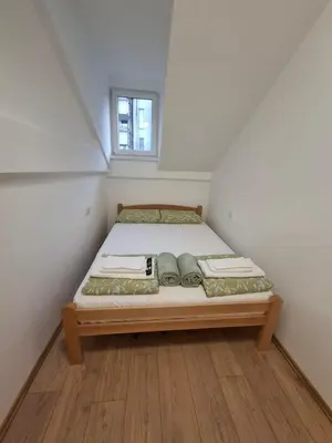 a small bed in a small room with a window at Vanja's Apartman in Belgrade