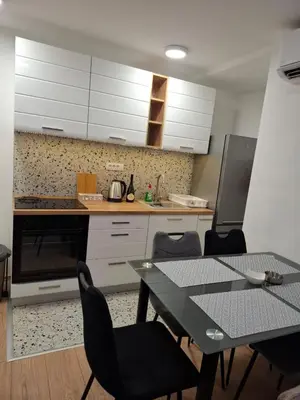 a kitchen with a table and chairs and white cabinets at Vanja's Apartman in Belgrade
