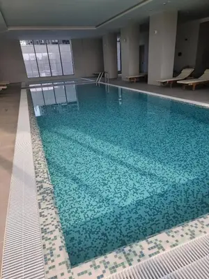 a large swimming pool with blue water in a building at Exclusive apartman BW Terraces in Belgrade