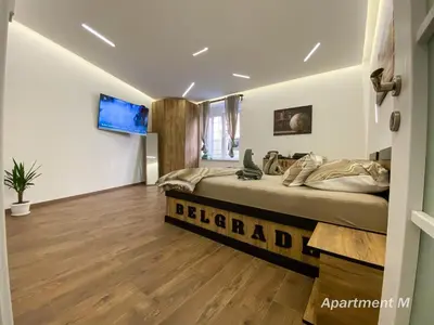 a bedroom with a bed and a television on the wall at Apartman M in Belgrade