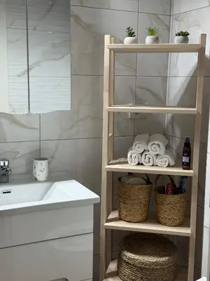 a bathroom with a shelf with towels and a sink at DILL apartman Arandjelovac in Arandjelovac