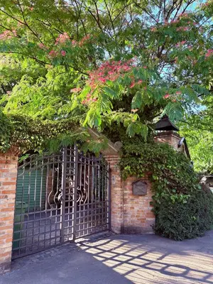 a gate with a tree with pink flowers on it at Tiny Home L&B in Belgrade