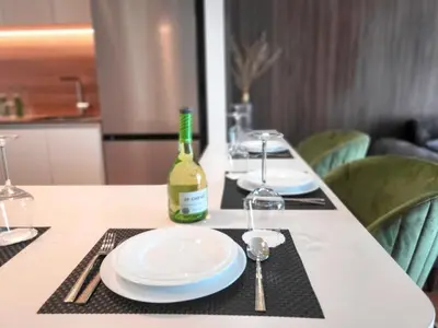 a table with white plates and a bottle of wine at Arkadija Lux Apartment River And Tower View in Belgrade
