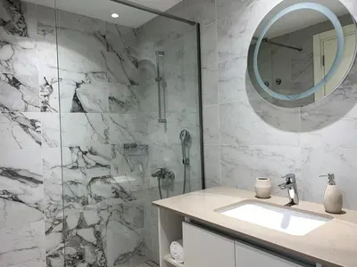 a bathroom with a sink and a shower with a mirror at Arkadija Lux Apartment River And Tower View in Belgrade