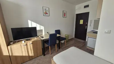 a room with a desk with a television and a kitchen at Banjica 202 in Voždovac