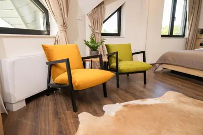 a room with two yellow chairs and a bed at Pećina Stroga - Bjelica Winery Rooms in Sremski Karlovci