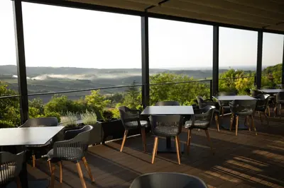 a restaurant with tables and chairs on a balcony at Pećina Stroga - Bjelica Winery Rooms in Sremski Karlovci