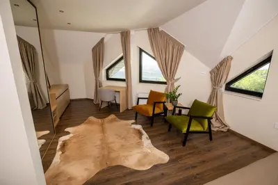 a living room with a table and chairs and a rug at Pećina Stroga - Bjelica Winery Rooms in Sremski Karlovci