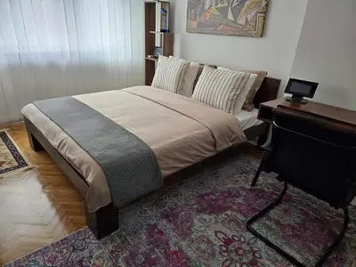 a bedroom with a bed with a desk and a table at Kostas Apartment in Belgrade