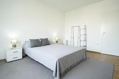 a white bedroom with a large bed and two lamps at Cozy Stay 2 Min from Saint Sava Temple in Belgrade