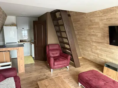 a living room with a red chair and a staircase at 3A vikendica Slankamen in Stari Slankamen