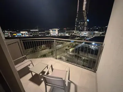 a balcony with a table and chairs and a city at night at BW AQUA Joi Lux Apartment in Belgrade