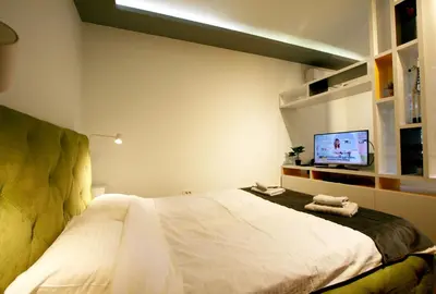 a bedroom with a bed with a tv on the wall at Studio Intriga in Belgrade