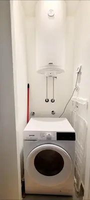 a washing machine in a white room with a light at BW Queen Apartman 412-whit free garage parking in Belgrade