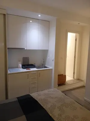 a kitchen with white cabinets and a bed in a room at Senjak studio apartment, near Belgrade fair in Belgrade