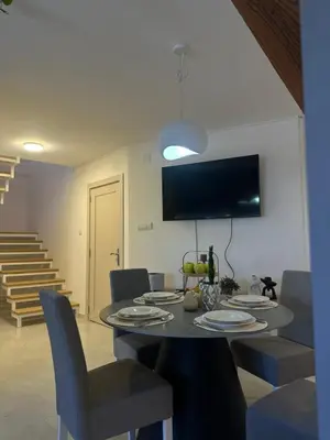 a dining room with a table with chairs and a television at Iva Lux in Belgrade