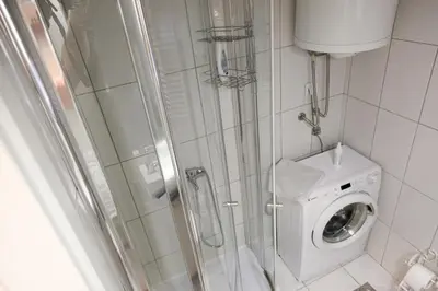 a shower stall with a washing machine in a bathroom at Purple and Green in Belgrade