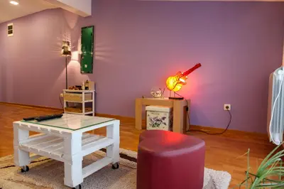 a living room with purple walls and a table and a lamp at Purple and Green in Belgrade