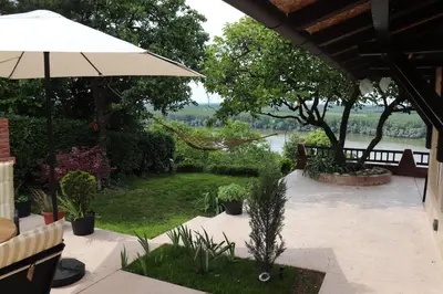 a patio with an umbrella and a view of a river at Panorama Beska in Beška